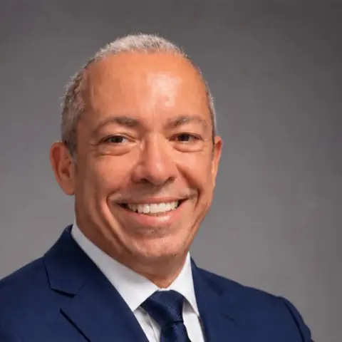 Estevão Pinheiro, de terno azul-marinho e gravata, sorrindo (retrato do Estevão)
